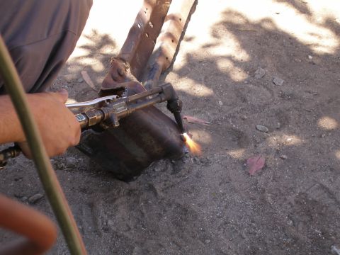 1969 Ford F-250 - Metal part being cut with a torch in an outdoor setting.