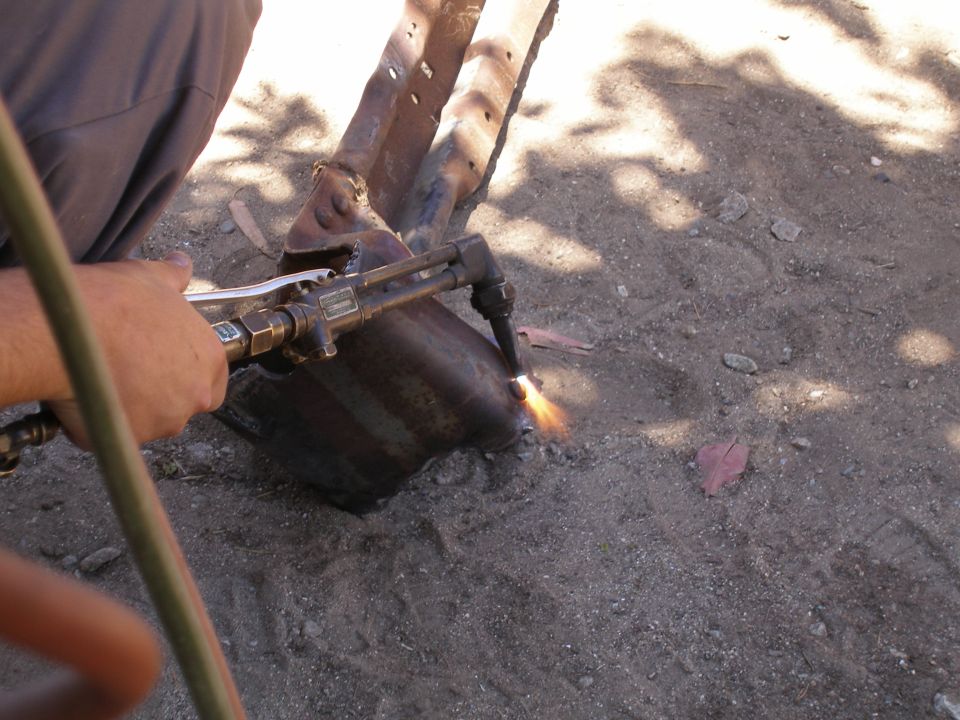 Person cutting rusted metal with a torch, sparks flying