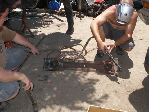 1969 Ford F-250 - Two men work on welding a rusty truck frame in an outdoor setting.