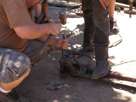 1969 Ford F-250 - Workers are using tools to shape or repair a metal part on the ground.