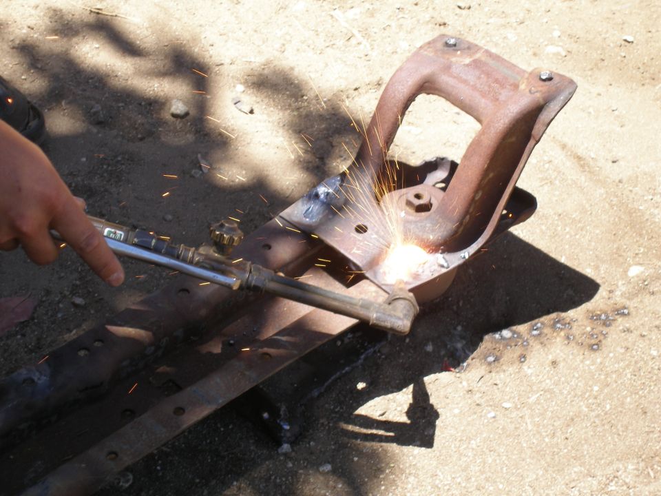 Welding a rusty, cast iron suspension part with sparks flying