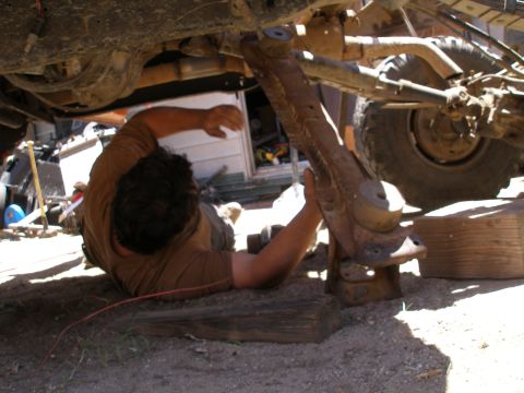 1969 Ford F-250 - A person is working on the suspension of a vehicle, which is raised on blocks.