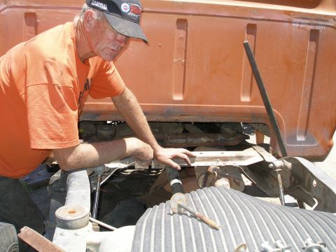 1969 Ford F-250 - A man works on the engine of an orange 1969 Ford F-250 truck.