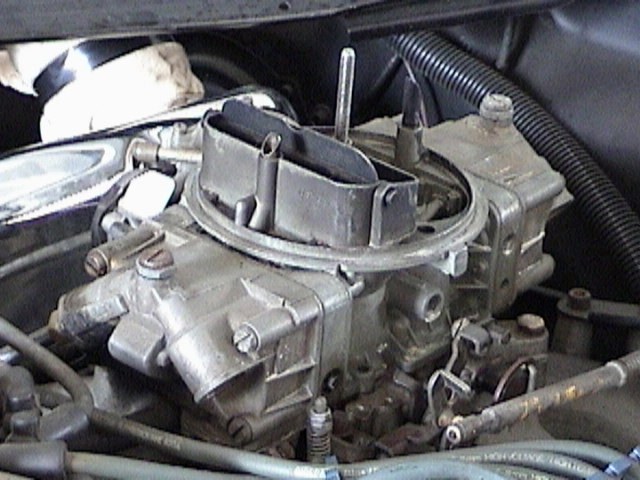 Close-up of a carburetor with a black air cleaner housing and metal components