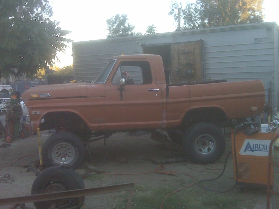 Orange pickup truck with lifted suspension, seen from the side