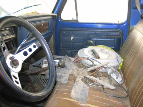 1979 Ford F-150 - The interior of a 1979 Ford F-150 shows an aftermarket steering wheel and various parts scattered on the passenger seat.