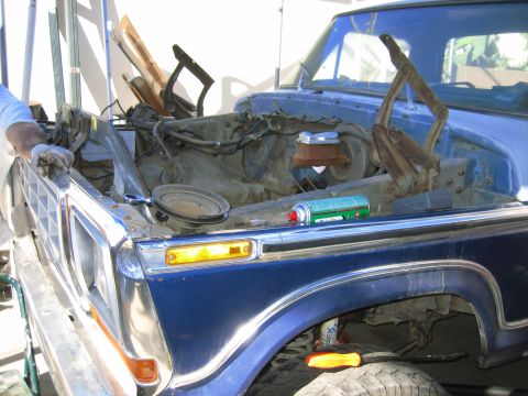 1979 Ford F-150 - The engine bay of a blue 1979 Ford F-150 is open for maintenance, with tools and a spray can visible.