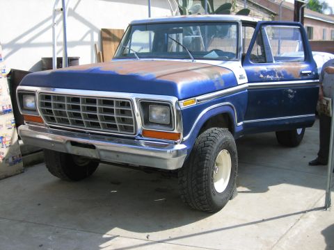 1979 Ford F-150 - A blue 1979 Ford F-150 pickup truck with a rusty hood and an open driver's door sits on a concrete surface.