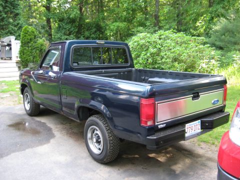 1989 Ford Ranger - Rear three-quarter view of a dark blue 1989 Ford Ranger pickup truck with a chrome accent panel on the tailgate.
