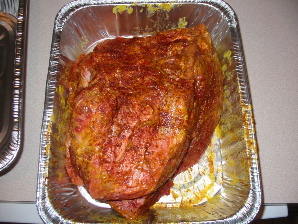Raw meat seasoned with spices in a foil pan