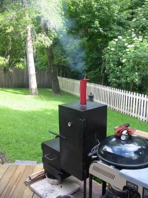 1992 Ford Bronco - A black smoker and a Weber grill are set up in a backyard, with smoke rising from the smoker.