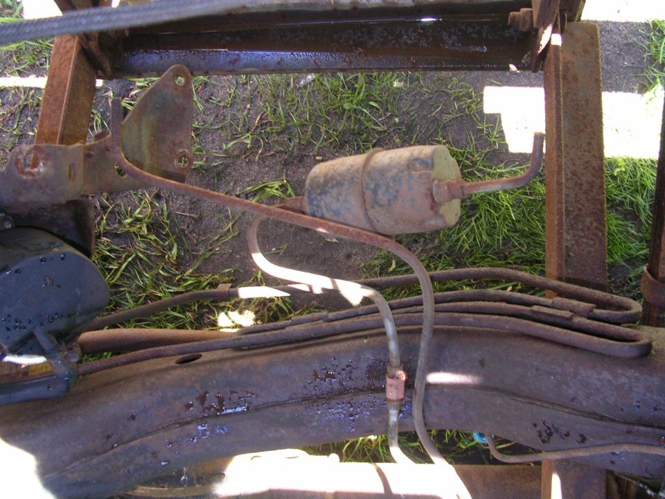 Undercarriage of a rusty vehicle showing a fuel filter and brake lines