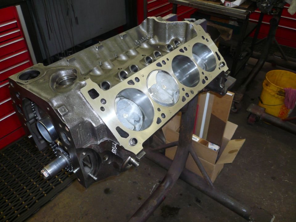 Engine block on a stand in a garage. Pistons are visible inside the cylinders