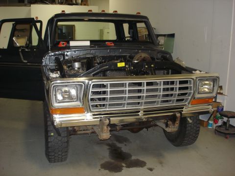 1979 Ford F-250 - The front of a 1979 Ford F-250 pickup truck is shown with its hood open, revealing the engine compartment.