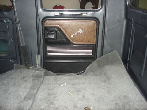 1979 Ford F-250 - The interior of a truck shows a brown and black door panel with a crank window and carpeted floor.