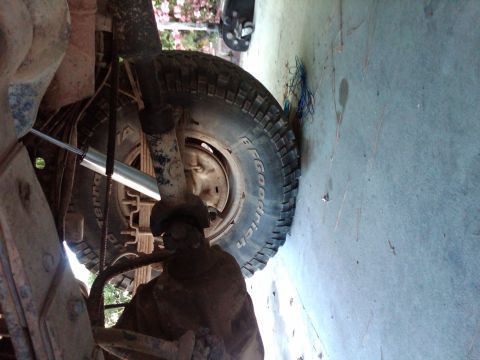 1982 Ford Bronco - A close-up view of a vehicle's undercarriage reveals its suspension components and a tire.