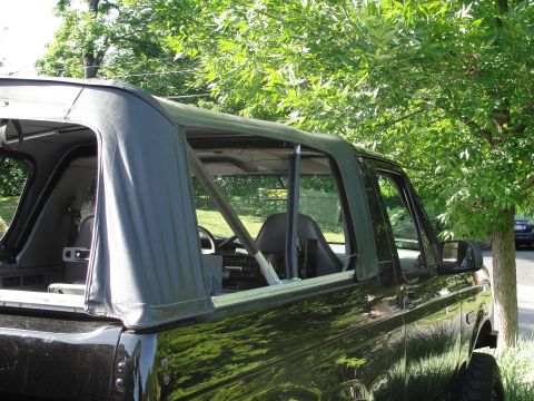 1995 Ford Bronco - Side view of a black soft-top SUV with a visible roll cage and aftermarket wheels.