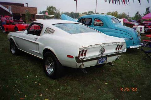 1968 Ford Mustang - White 1968 Ford Mustang fastback parked next to a blue sedan at an outdoor car show.