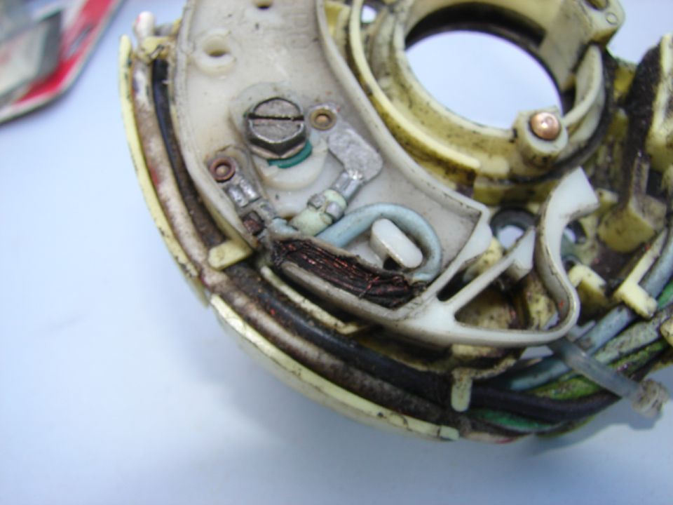 Close-up of a worn electrical component with exposed copper wiring and plastic casing