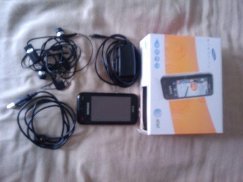 1995 Mercury Cougar - A Samsung phone, earbuds, charger, and its original packaging are laid out on a fabric surface.