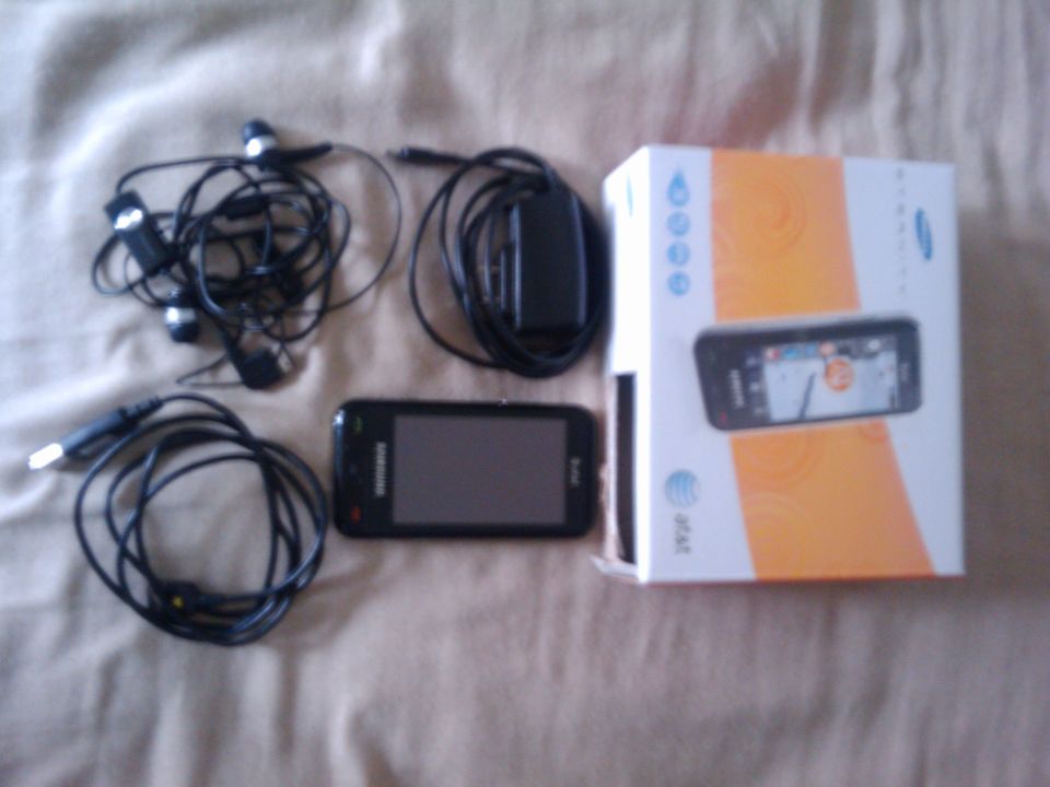 Samsung phone, earbuds, charger, and box on a textured surface