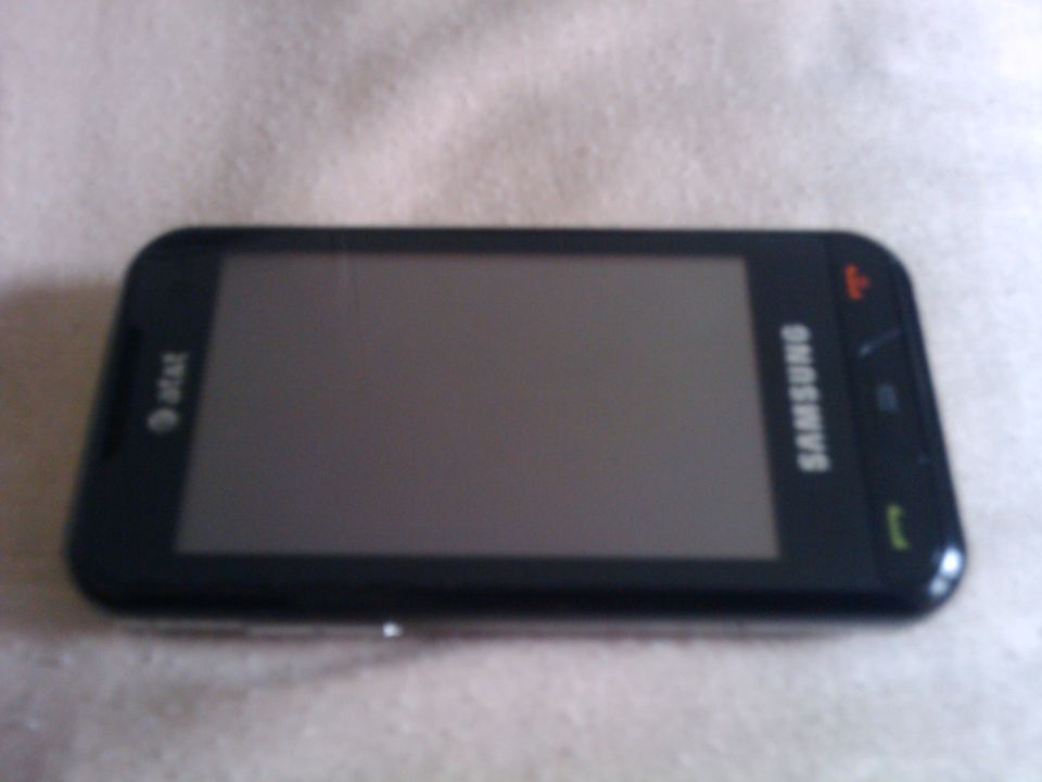 Black Samsung smartphone with AT&T logo, lying flat on a textured surface