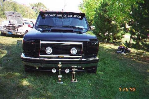 1994 Ford F-150 - A black Ford truck is parked on grass with trophies displayed in front, while another vehicle sits with its hood open in the background.