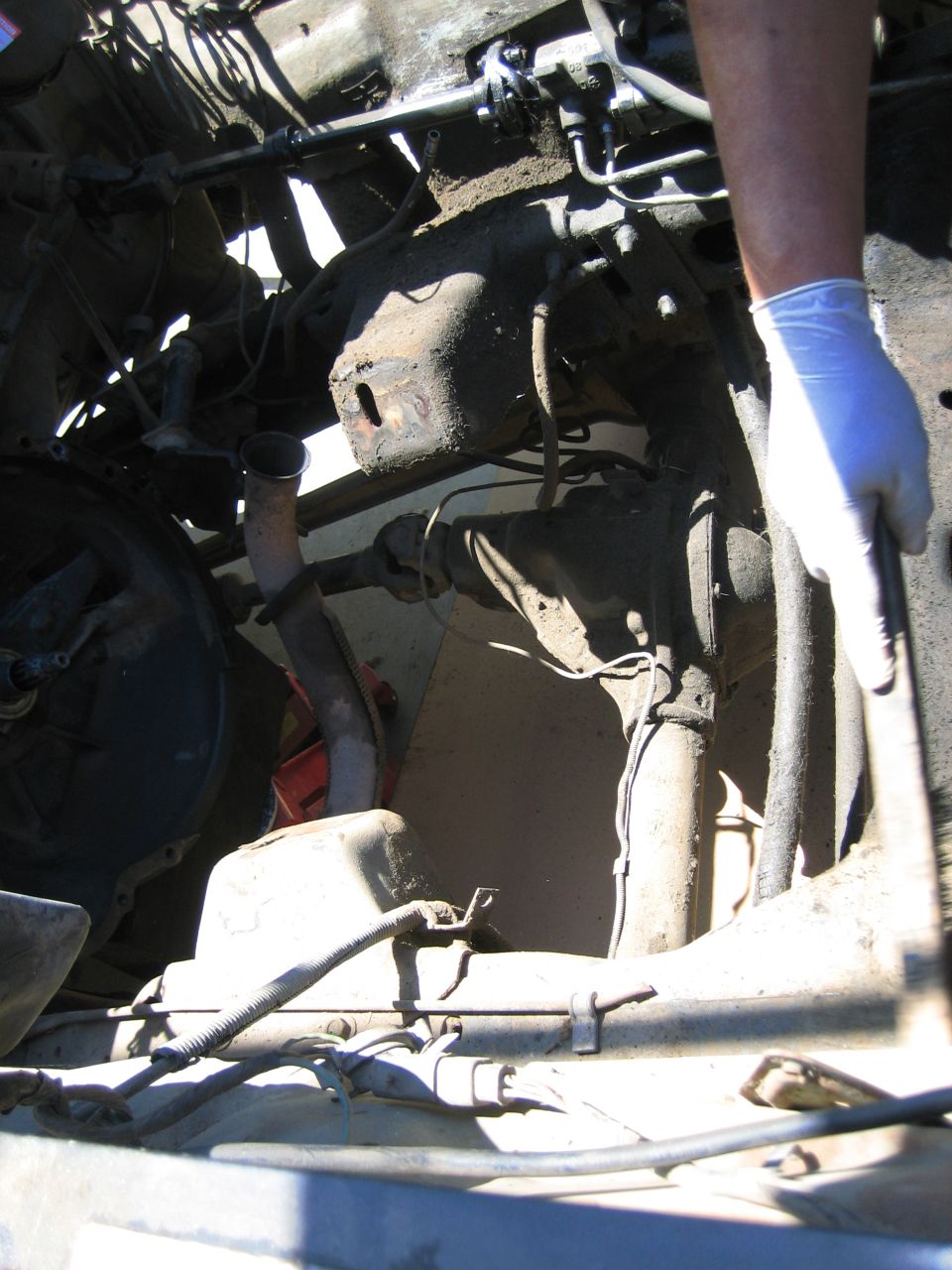 Close-up of a vehicle's engine bay with a person in a glove working on it
