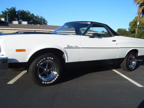 1973 Ford Ranchero - A white 1973 Ford Ranchero pickup truck is shown from the side, parked in a lot under a clear blue sky.