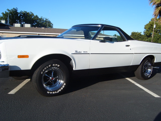 White 1973 Ford Ranchero with black trim and hood scoop, parked in a lot