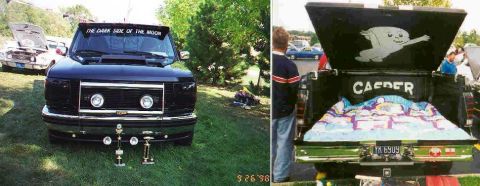1994 Ford F-150 - Front view of a black Ford F-150 truck with custom windshield text and trophies on the ground.