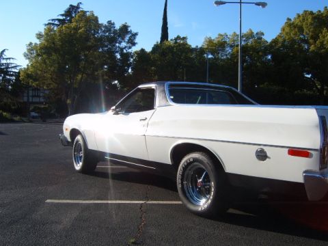 1973 Ford Ranchero - A white 1973 Ford Ranchero pickup truck is seen from the side, a black stripe along the lower body and chrome wheels.