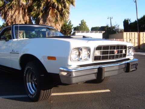 1973 Ford Ranchero - A white 1977 Ford Ranchero is parked outdoors, with palm trees and buildings in the background.