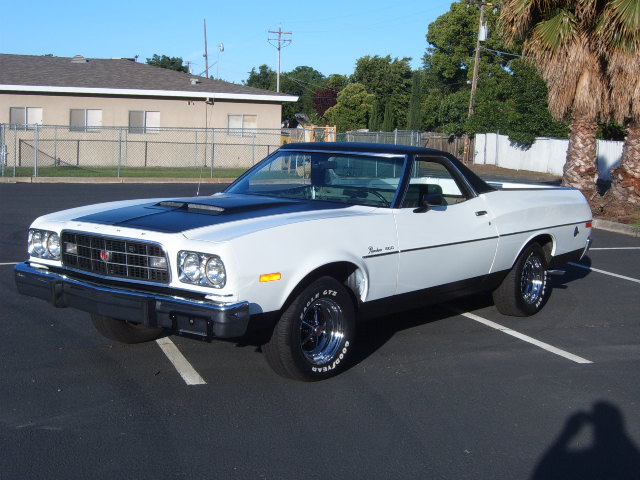 White 1973 Ford Ranchero with black hood and roof, parked in a lot