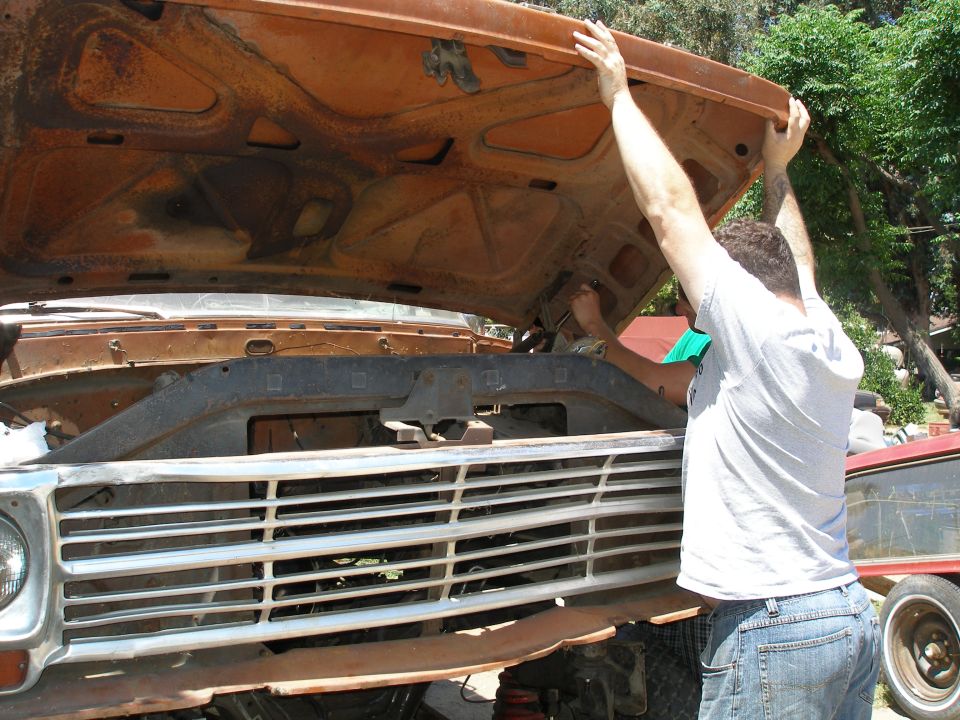Orange truck with chrome grille and open hood, man working on engine