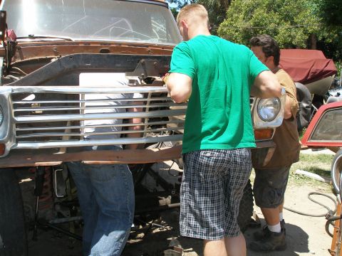 1969 Ford F-250 - Two men examine the front grille of a vintage truck, possibly a 1970s model.