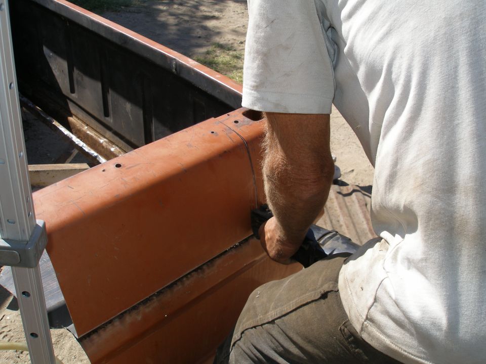 Orange pickup truck bed being worked on, close-up view