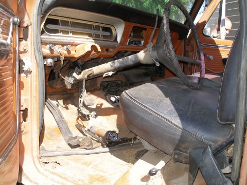 1969 Ford F-250 - The worn interior of an old truck shows a rusty dashboard, cracked steering wheel, and torn seat.