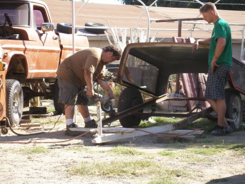 1969 Ford F-250 - Two men work on a disassembled Ford truck cab in an outdoor setting.