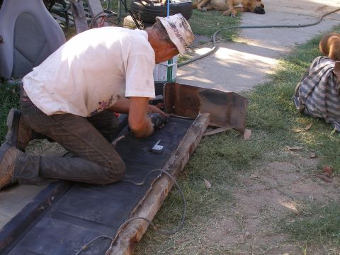 1969 Ford F-250 - Man grinds metal part outdoors, with dogs resting nearby.