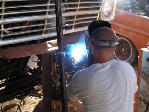 1969 Ford F-250 - A mechanic is welding the frame of a truck, with sparks flying from the welding torch.