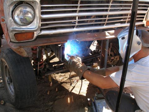 1969 Ford F-250 - Welding work on the front end of a classic Ford truck, with a prominent chrome grille and headlight visible.