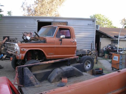 1969 Ford F-250 - This orange truck cab and chassis appears to be undergoing restoration work, with its front end prominently displayed.