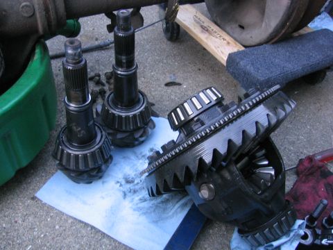1989 Ford Bronco - Close-up of differential components, including pinion gears and ring gears, on a paved surface.