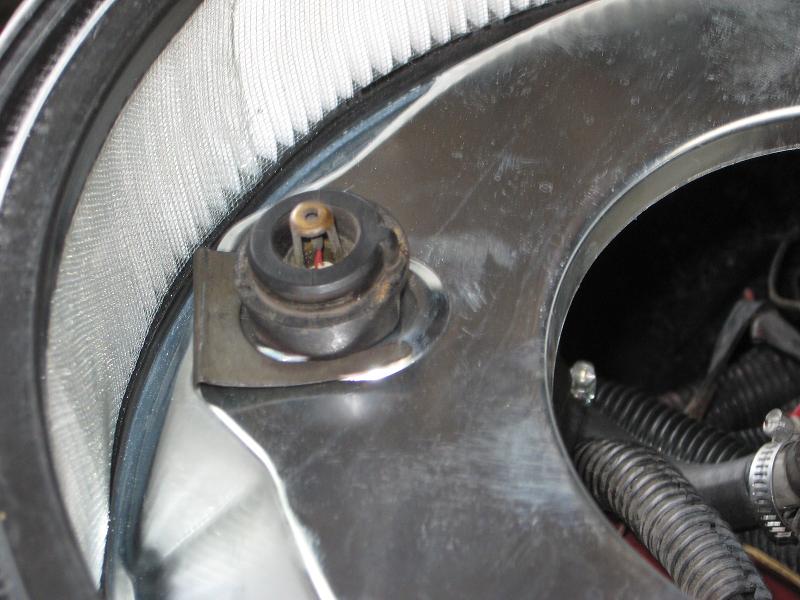 Close-up of a vehicle's air filter housing with a rubber seal and metal bracket