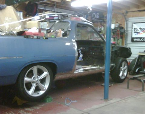 1971 Ford Ranchero - A blue 1971 Ford Ranchero is parked in a garage, showing signs of repair work with its door open and front fender missing.