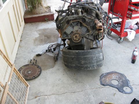 1969 Ford F-250 - Engine removed from vehicle and resting on a stand, with associated parts scattered on the ground.
