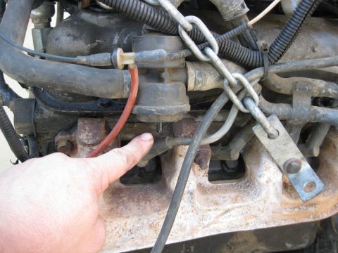 1969 Ford F-250 - A finger points to a component on a dirty engine. The registry claims it is a 1969 Ford F-250, but this is unconfirmed.