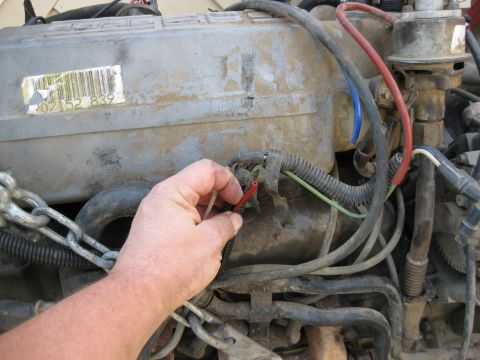 1969 Ford F-250 - Close-up of engine wiring being repaired, with a barcode sticker on the engine cover.