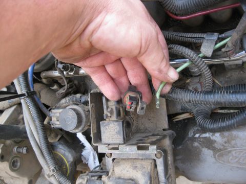 1969 Ford F-250 - A hand is shown disconnecting a wire from a Ford engine component, highlighting the complexity of automotive wiring.